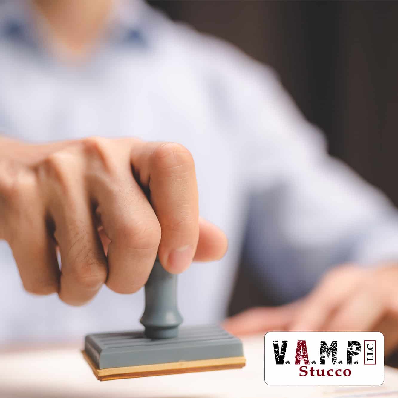 Man placing an approval stamp on a stucco project permit, signifying V.A.M.P. Stucco's commitment to quality and reliable service as outlined in our meta description.